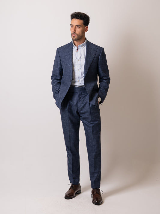 A man stands with hands in the pockets of his light blue linen-wool suit