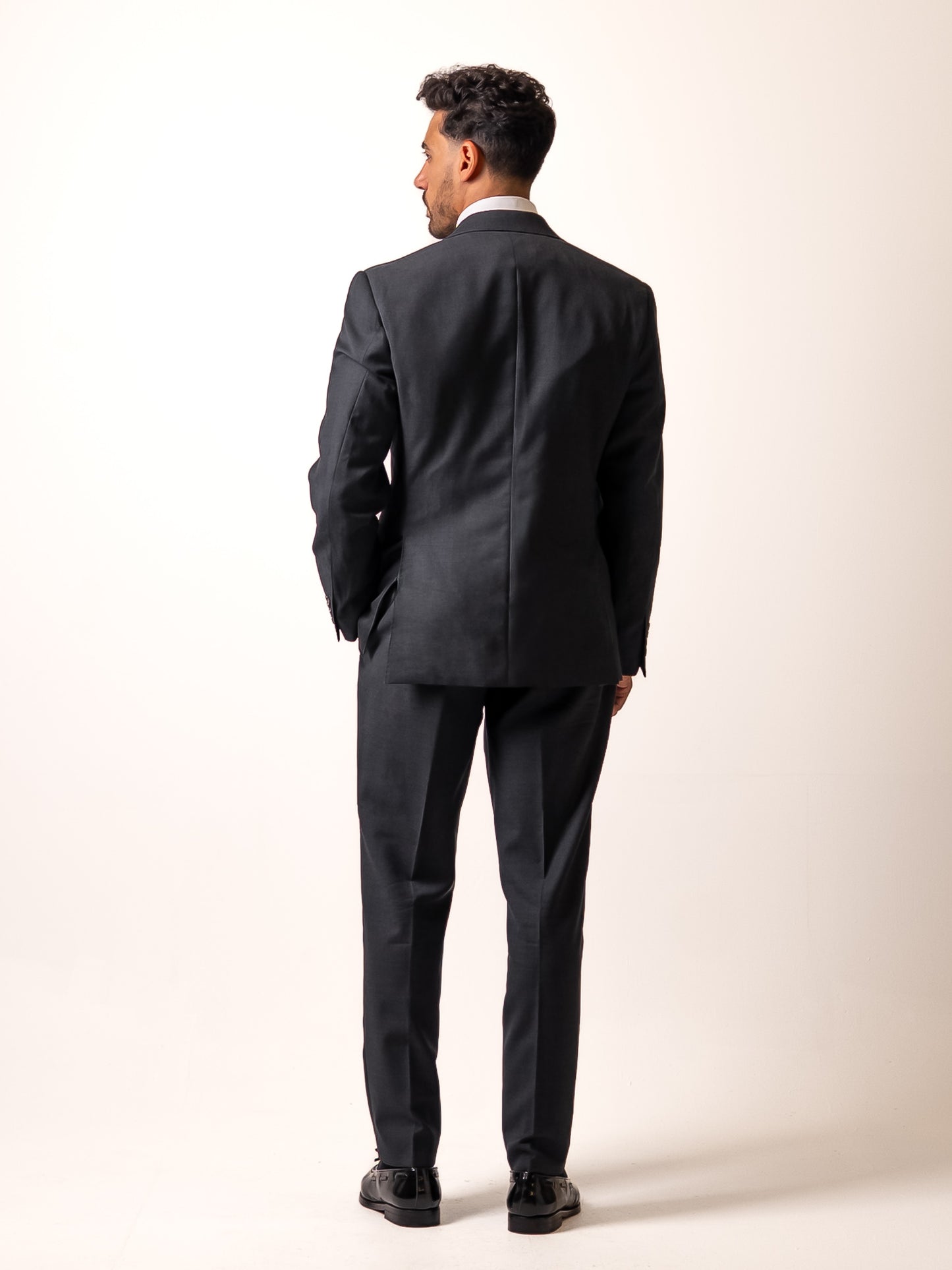Back view of made-to-measure dark sharkskin grey trousers. Showcasing the refined back pocket, double pleats, and uninterrupted silhouette of Aster Legacy’s Gurkha-inspired cut.
