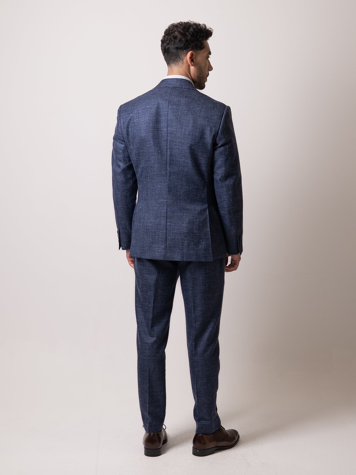 Back view of the tailored light blue linen-wool suit, showcasing the trousers’ elegant fall and refined rear profile