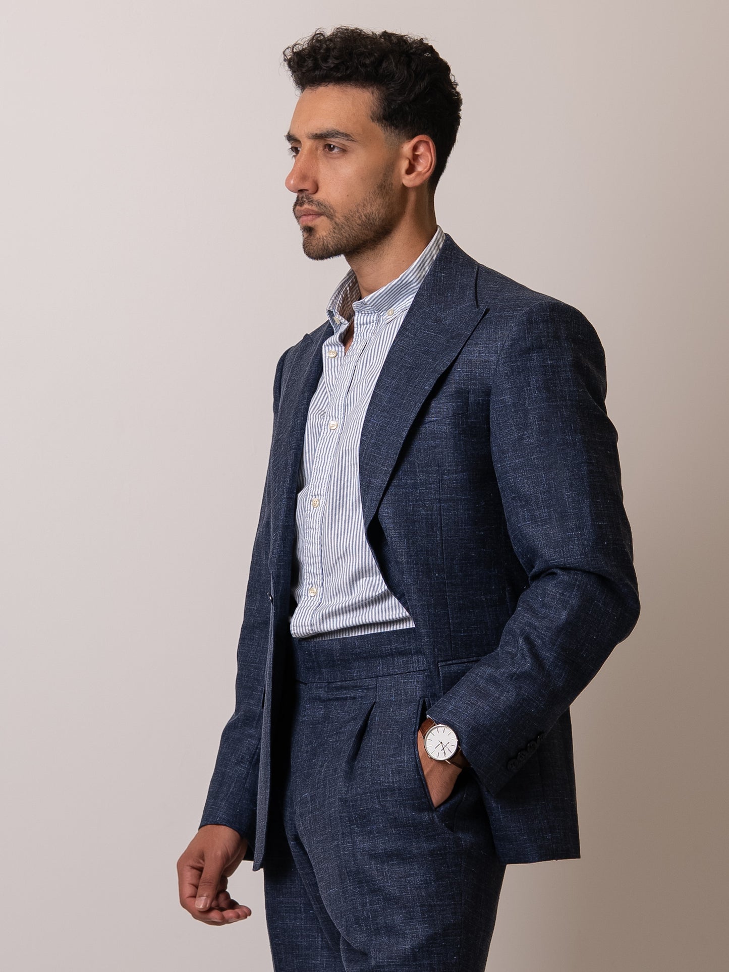 Side view of a man in a light blue linen-wool blazer with hand resting in the trousers  pocket