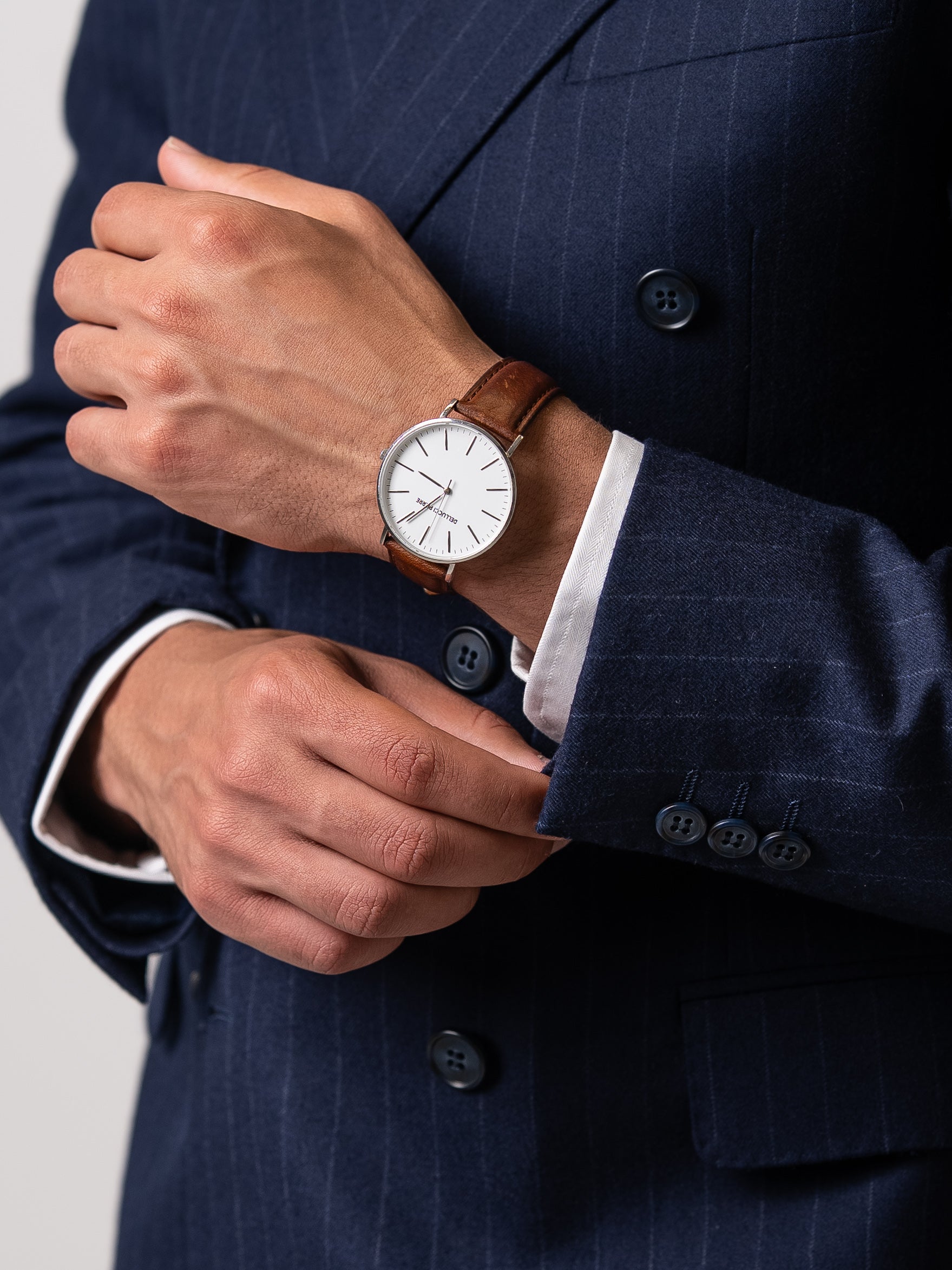 Close-up of functional cuff buttons on a chalk stripe blazer, paired with a classic wristwatch  A hallmark of true tailoring and understated sophistication. 