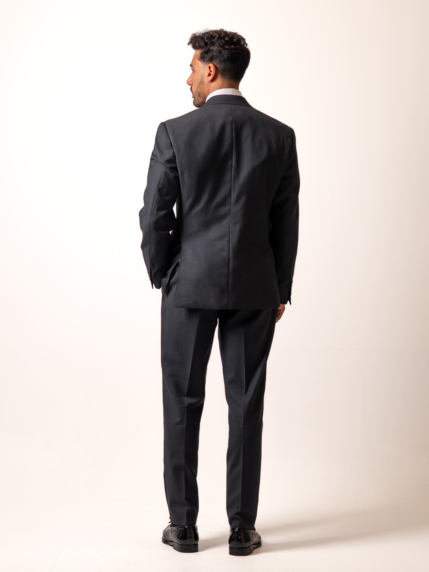 Back view of made-to-measure dark sharkskin grey trousers. Showcasing the refined back pocket, double pleats, and uninterrupted silhouette of Aster Legacy’s Gurkha-inspired cut.