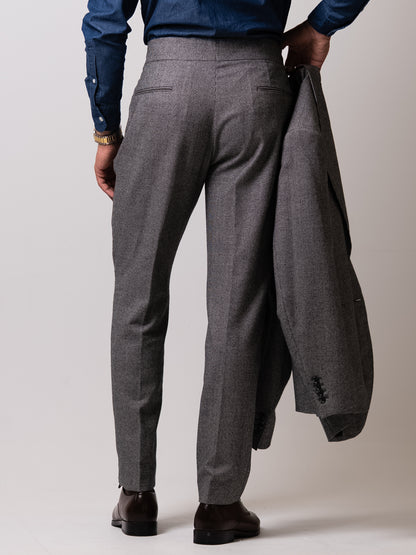 Back view of the light grey houndstooth trousers — double pleats, side adjusters, and a refined back pocket preserving an uninterrupted, sculpted line