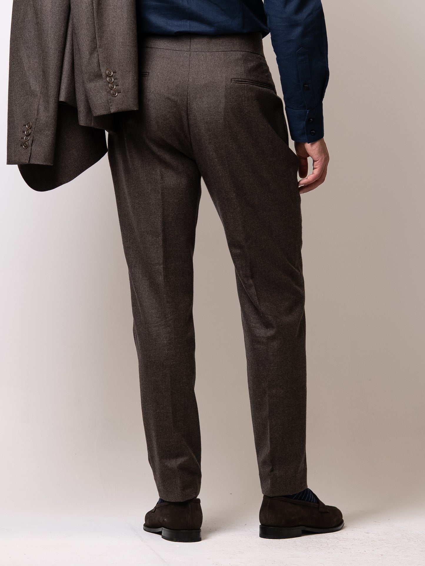 Back view of deep brown houndstooth trousers highlighting the single welt back pocket 