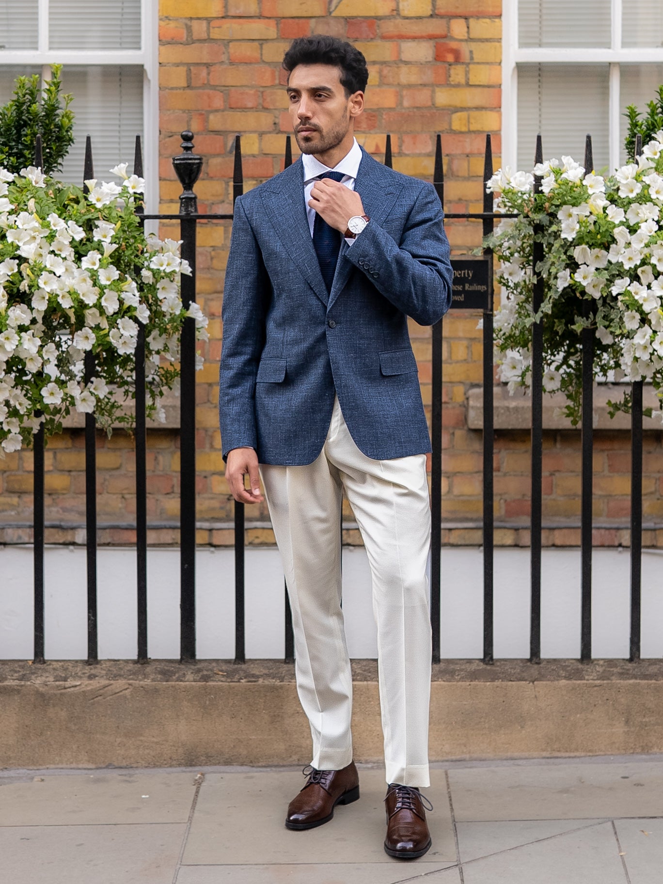 Tailored white trousers styled with a light blue linen-wool blazer on a London street 